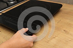 Woman hand turn on induction stove. Finger touching sensor button on induction or electrical hob. Modern kitchen appliance