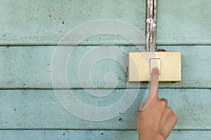 Woman hand are turning on or off to old electrical light switch with old vintage light blue wood wall background