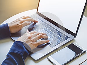 Woman hand type on Laptop Keyboard with smart phone Business concept