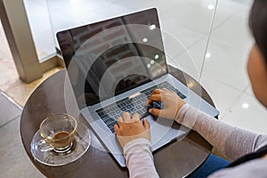 Woman hand typing laptop keyboard at round coffee table