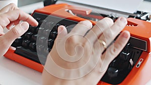 Woman hand typing on red vintage typewriter