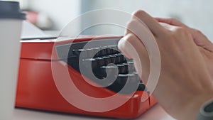 Woman hand typing on red vintage typewriter