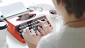 Woman hand typing on red vintage typewriter