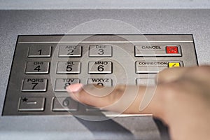 Woman hand typing security code on atm