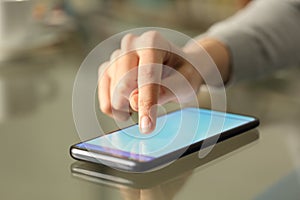 Woman hand typing on a smart phone over a desk