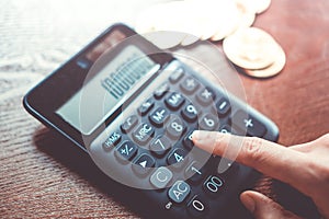 Woman hand use calculator with a stack of Bitcoins coins as symbol of cryptocurrency digital money in the future blockchain as