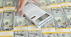 Woman hand using a calculator counts a large number of dollar bills