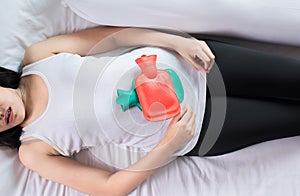 Woman hand using hot water bag or bottle on her belly on bedroom,Female suffering from abdominal pain,Period cramps