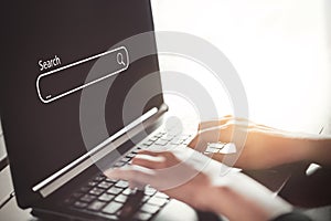 Woman hand using keyboard laptop with search bar icon on screen at coffee shop. Business technology and freelance concept