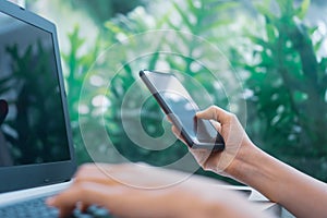 Woman hand using laptop or smartphone to work study on work desk with clean nature background background. Business, financial,