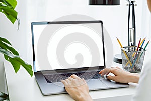 Woman hand using laptop on the table in house, mock up of blank screen.