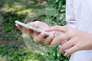 Woman hand using smart phone on green park background