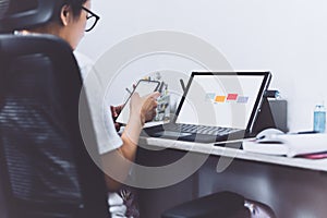 Woman hand using smart phone and laptop at home office.