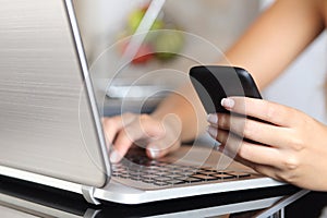 Una mujer mano elegante teléfono escribiendo computadora portátil sobre el 