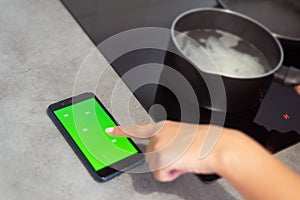 Woman hand using smartphone in kitchen with green screen