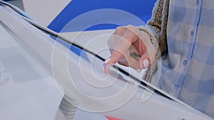 Woman hand using touchscreen display of floor standing white tablet kiosk