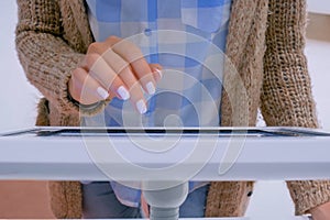 Woman hand using touchscreen display of floor standing white tablet kiosk
