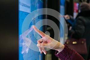 Woman hand using touchscreen display of kiosk with city map - close up