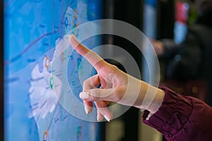 Woman hand using touchscreen display of kiosk with city map - close up