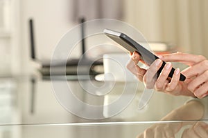 Woman hand using wifi on phone with a router in background
