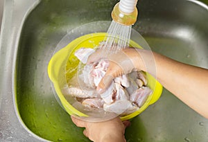 Woman hand wash chicken middle wings with water