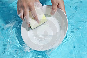 Woman hand washing ceramic dish in clean water
