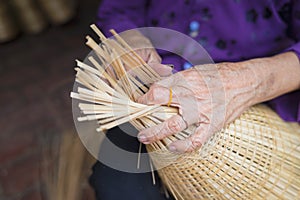 Woman hand weaving tropical bamboo fish trap in traditional crafts village in Vietnam