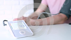 Woman hand and white electric tonometer on table for measuring blood pressure Healthy concept. Measurement of pressure