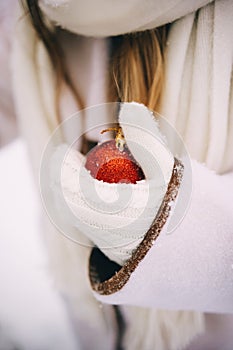 Woman hand in white mitten hold red bauble