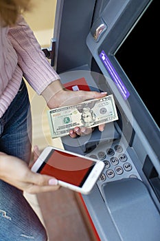 Woman hand withdrawing money from outdoor bank ATM