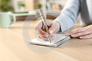 Woman hand witing on a notepad on a desk at home