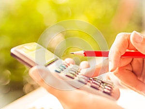 Woman hand working with calculator and holding red pencil