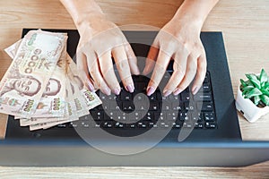 Woman hand working and make money online from home with banknotes  on computer laptop during covid-19 pandemic