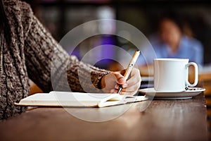 Woman hand writing on notebook in the cafe