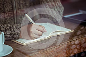 Woman hand writing on notebook in the cafe in rainy day