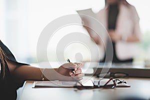 Woman hand writing on paper on clipboard