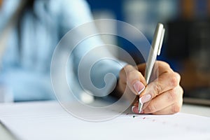 Woman hand writing with silver ballpoint pen in notebook closeup