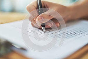 Woman, hand and writing a test with choice on clipboard for exam assessment, quiz and closeup of answer sheet. Paperwork