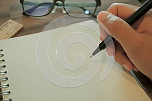 Woman hand is writing on white notebook.