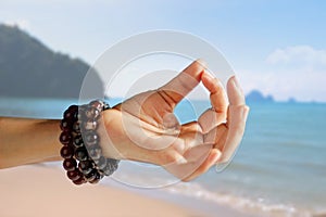 Woman hand yoga and meditation on the summer beach background