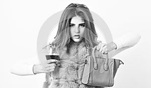 Woman with handbag hold glass of wine. Girl wear fashion fur vest while posing with bag. Luxury store concept. Elite
