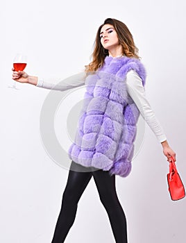 Woman with handbag hold glass of wine. Girl wear fashion fur vest while posing with bag. Luxury store concept. Lady