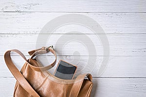 Woman handbag with phone on white wood table