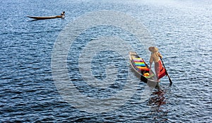 A woman with handcrafted colorful lotus fabrics on her boat in In Dain Khone village, on Inle Lake, Myanmar.