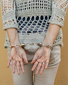 A woman is handcuffed while standing with her hands tied behind her back