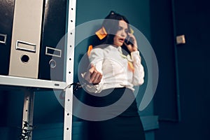 Woman handcuffed to metal rack.