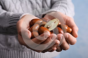 Woman with handful of fresh Ziziphus jujuba fruits on light background, closeup