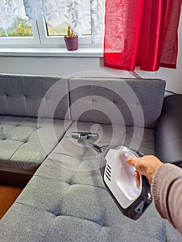 Woman with handheld vacuum cleaning on sofa