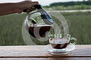 Woman handhold a coffee pot and drop to the glass