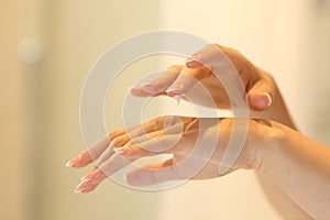 Woman hands applying moisturizer cream in the bathroom